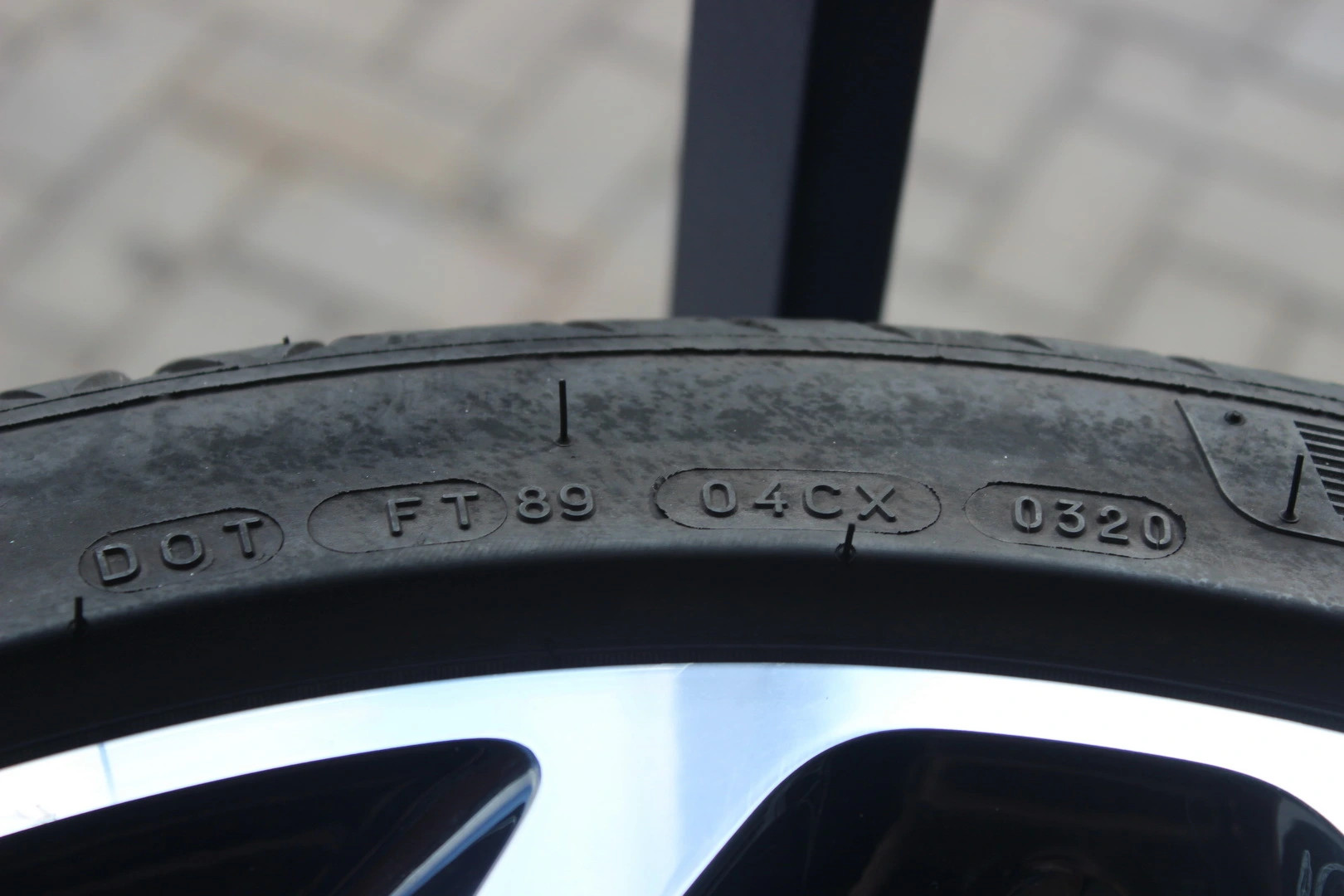 Detail pneumatiky s vyrazenými kódmi DOT, FT89, 04CX a 0320 na bočnici, zblízka.