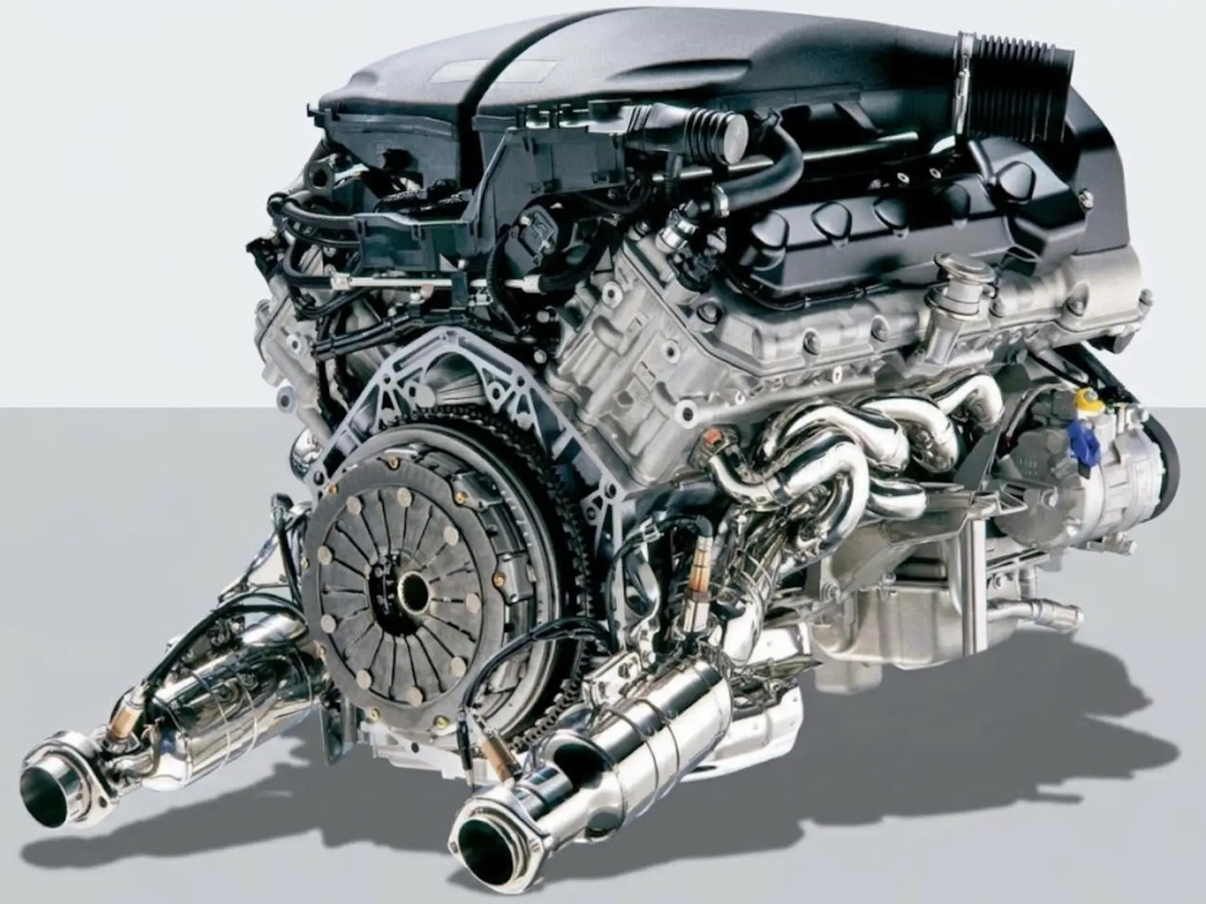 Detailný pohľad na rozobratý automobilový motor s hadicami, potrubím a kovovými komponentmi.